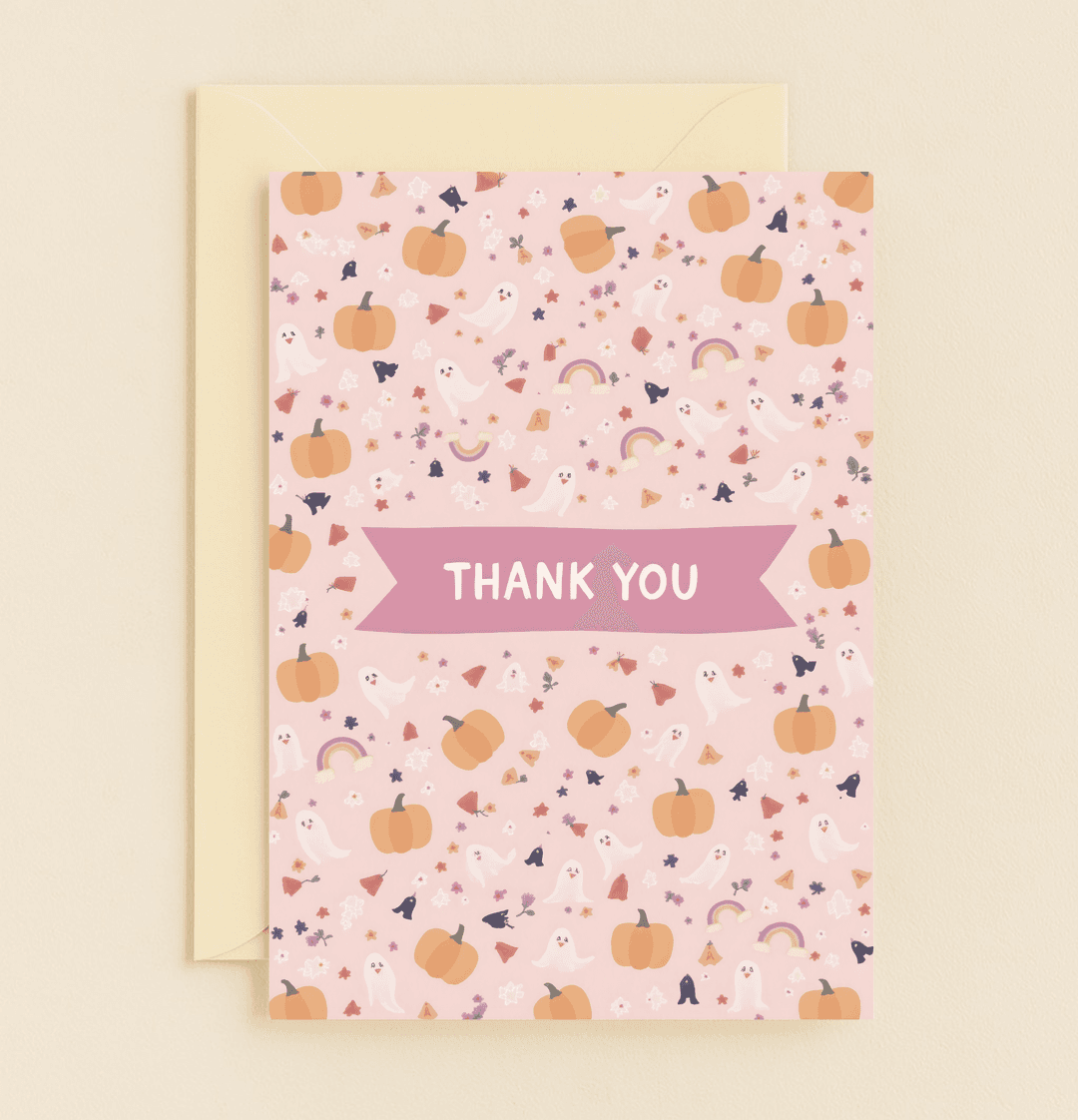 Celebrate gratitude with a whimsical card featuring charming pumpkins, ghosts, rainbows, bats, flowers, and leaves on a playful pink backdrop.
