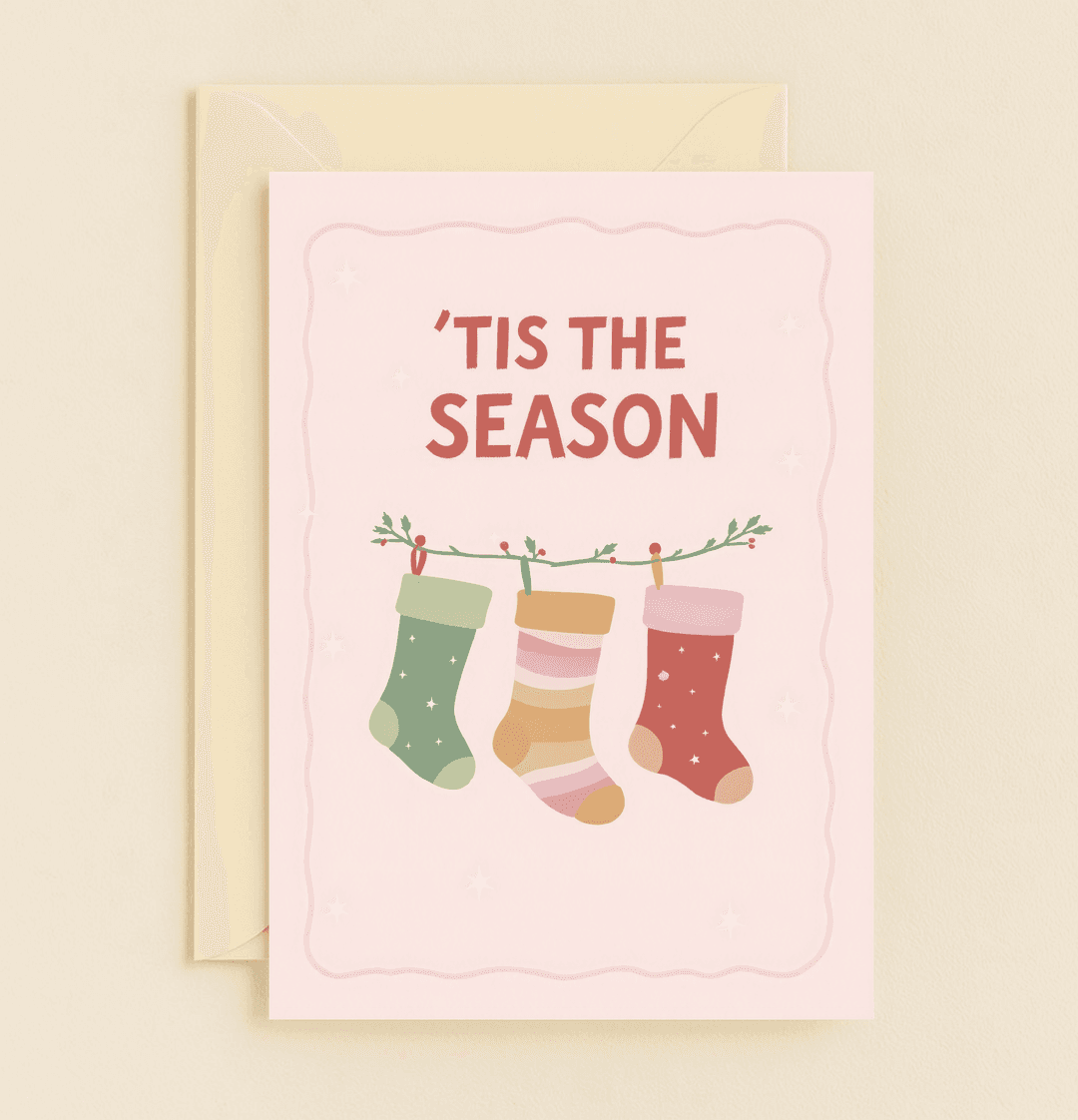Celebrate Christmas with our charming card featuring colorful stockings, festive berries, and twinkling stars on a pastel pink backdrop.