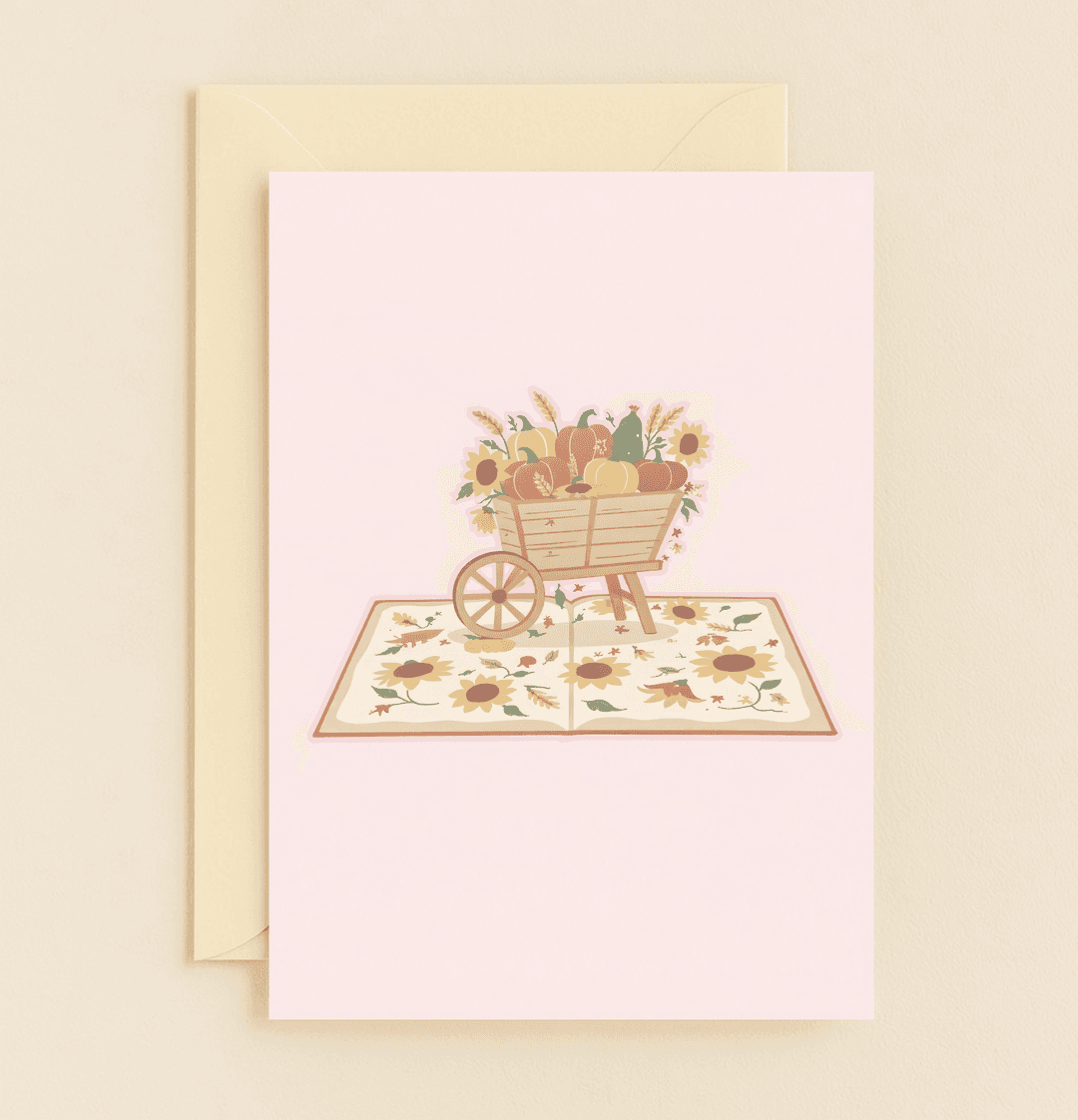 Celebrate Thanksgiving with a charming card featuring a wooden cart brimming with pumpkins, gourds, sunflowers, and autumn leaves against a soft pastel pink backdrop.